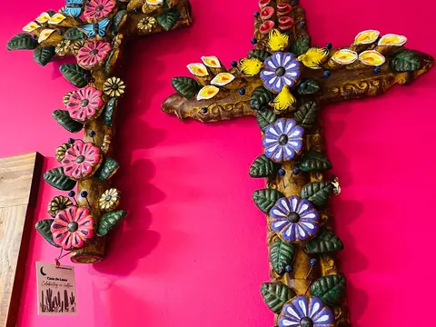Hand-carved wooden crosses decorated with colorful clay flowers and birds