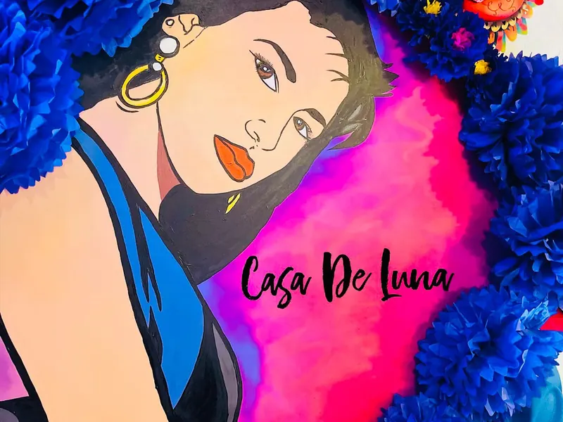 Hand-painted Selena mural surrounded by blue paper flowers inside Casa de Luna88